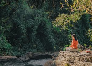 woman sitting in the woods in a meditation position
