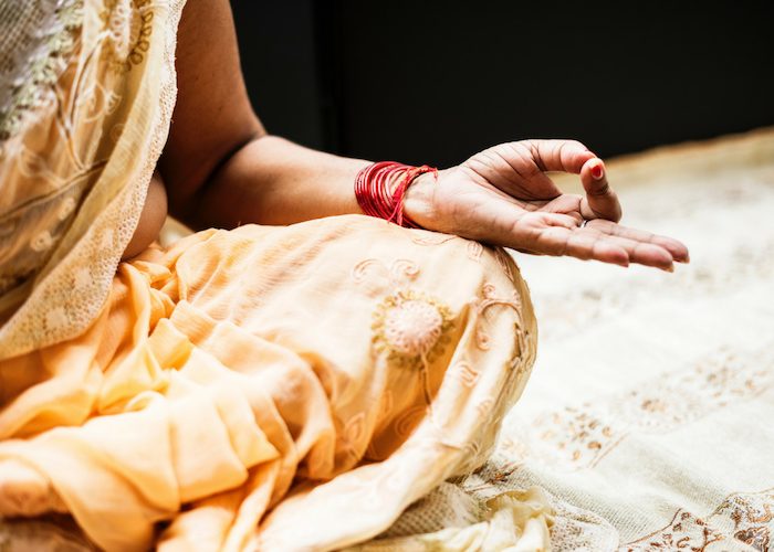 Indian woman in sari sitting in the meditation position with her hand on her knee
