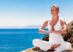 woman sitting in the quarter lotus meditation position by the sea