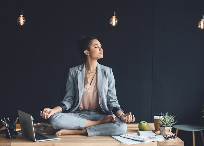 woman sitting on her work table and meditating in the office