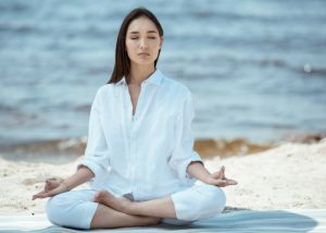 woman looking peaceful and meditating on a quiet beach 