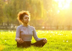 woman sat on the grass and meditating in the park