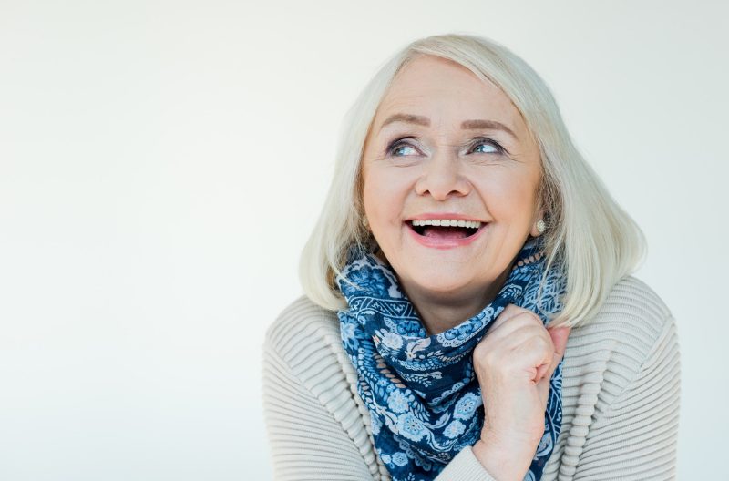 Happy old woman in a sweater and blue scarf