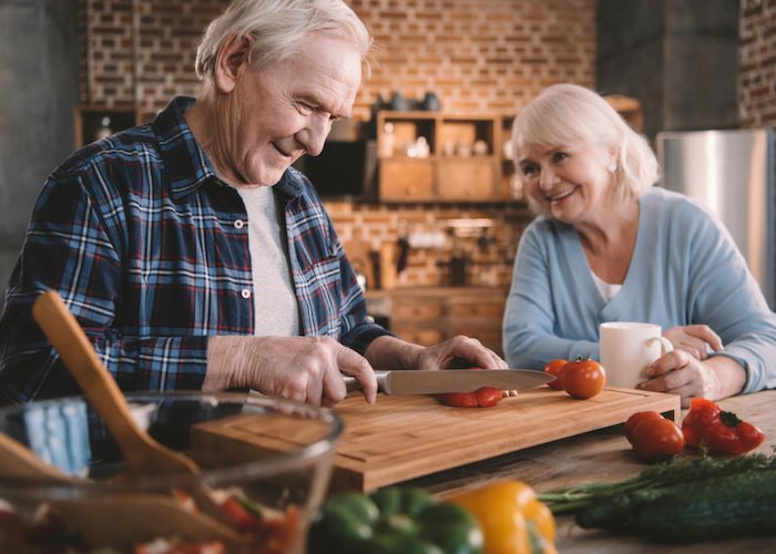 an old couple cooking with healthy fresh ingredients at home