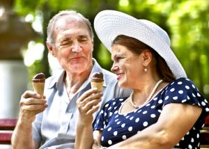 an old couple indulging in ice cream outdoors on a sunny day