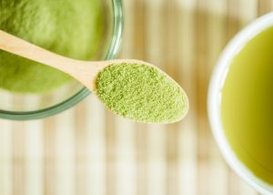 matcha green tea powder in a wooden spoon