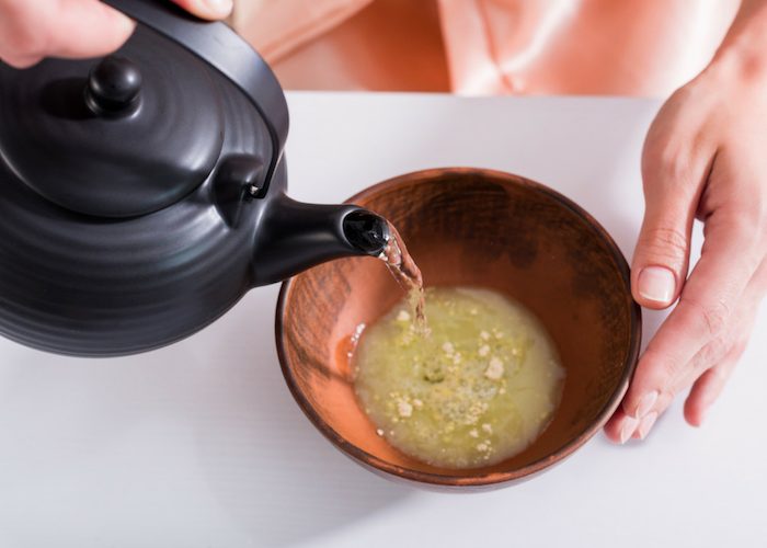 woman pouring hot water into a bowl of matcha green tea powder