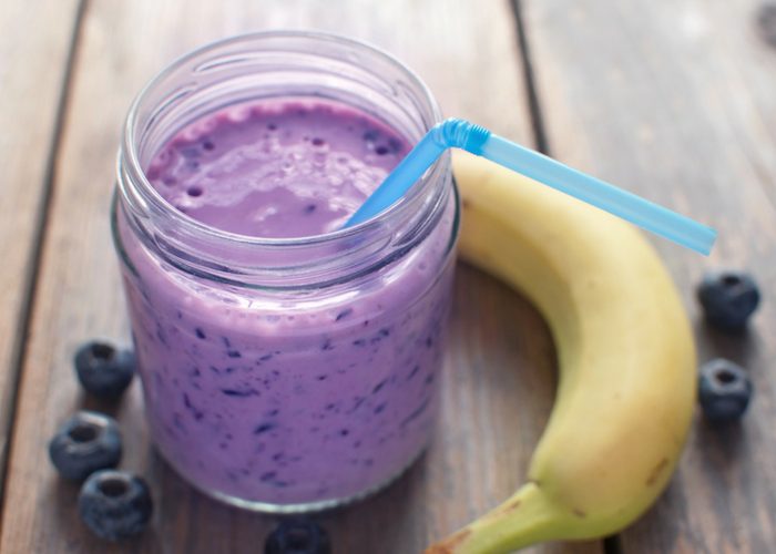 a blueberry and banana smoothie in a jar with a blue straw