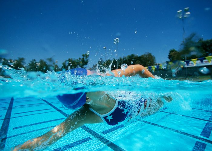 woman with a swimming cap swimming laps in an outdoor pool