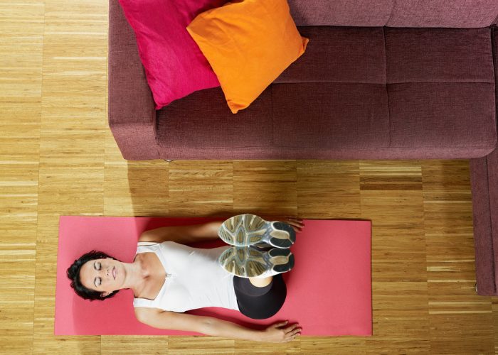 woman doing leg raise and hold ab exercises at home next to her couch