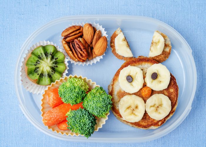 bento lunch box with broccoli, carrots, kiwi, almonds and banana pancake, organized using silicone cups