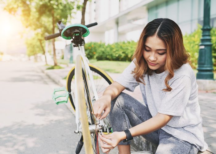 a young woman at the side of the road fixing her bicycle