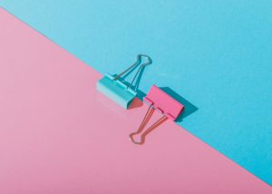 a flat lay of a blue and pink paper clip set on contrasting table backgrounds