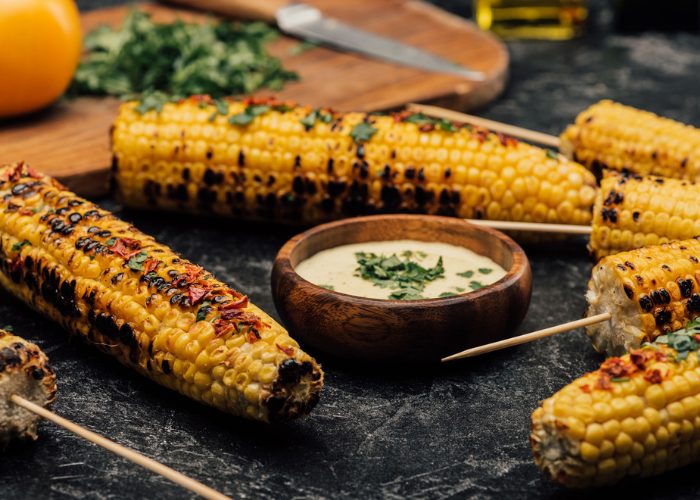 grilled corn on the cobs seasoned with paprika and parsley, served on black slate plates