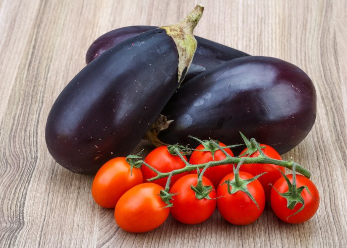 nightshade vegetables like eggplants and tomatoes on a wooden table
