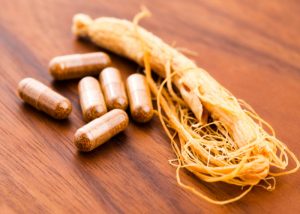 ginseng supplement capsules next to a fresh ginseng root 