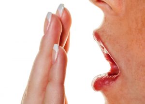 woman blowing onto the palm of her hand to smell her breath