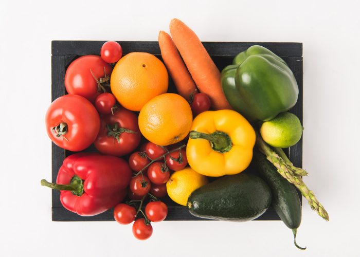 a basket full of fresh vegetables like peppers, tomatoes, carrots, eggplant, asparagus, cucumbers