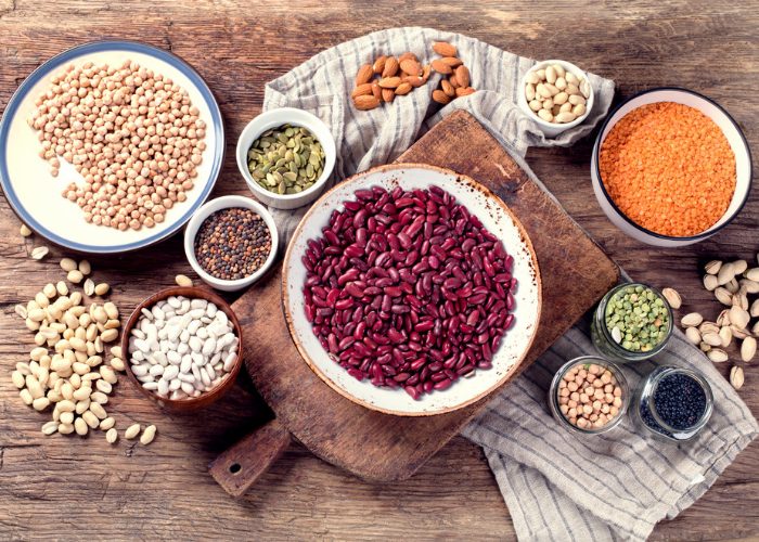 protein rich legumes such as chickpeas, kidney beans, and soy beans laid out on a wooden table