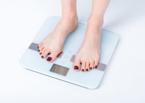 woman standing on electronic weight scale to measure how much she weighs