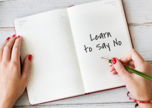 woman holding a green pencil with an open notebook that is opened to a page that says "learn to say no"