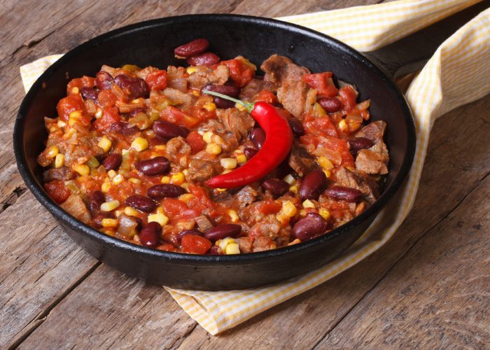 Homemade vegetarian, meat-free chili in a skillet, topped with a whole fresh red chili pepper