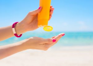 woman squeezing sunscreen out onto her hand at the beach