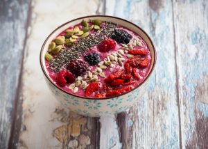 vegan gluten free breakfast bowl with smoothie, nuts, chia seeds, and mixed berries