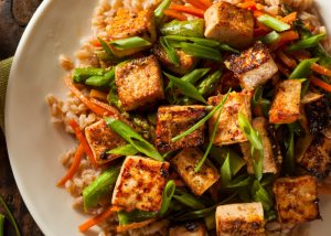 a healthy stir fried tofu dish with vegetables and rice on a plate