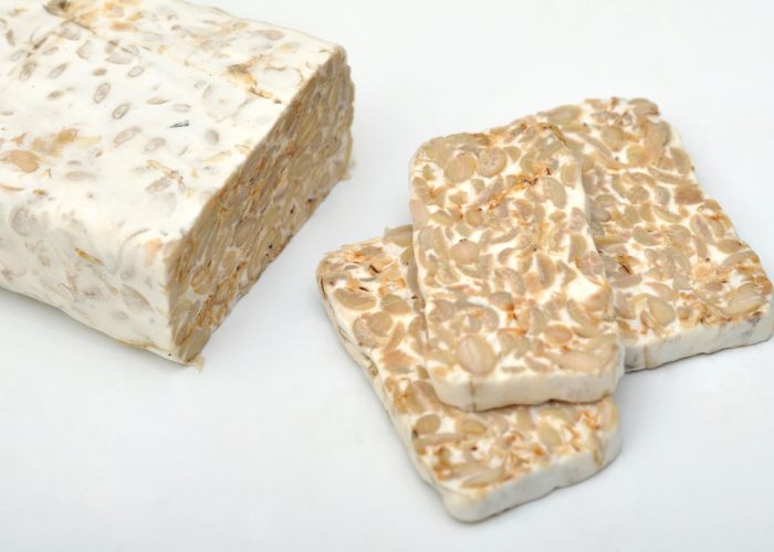 a block and three slices of tempeh, a well known vegan meat alternative