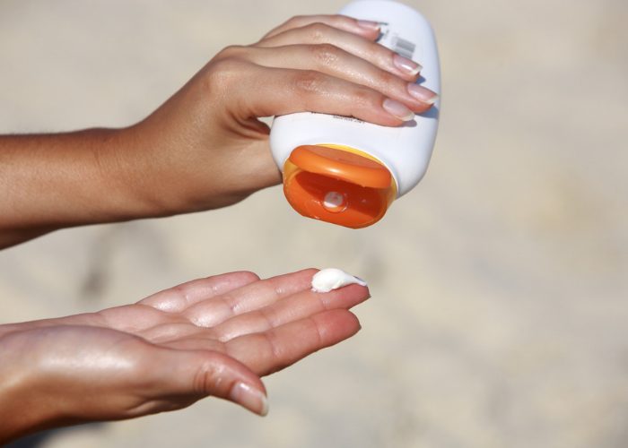 woman squeezing sunscreen out of a bottle onto her hand