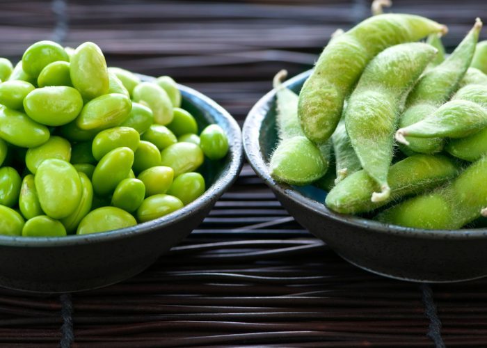 A dish of edamame beans still in its shell and another dish of de-shelled edamame beans