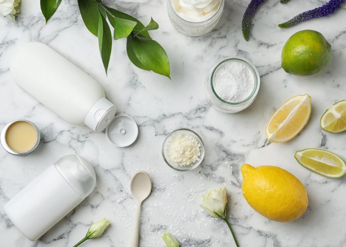 Homemade natural deodorant ingredients such as lemon, lime, lavender, baking soda, and bottles on a marble table
