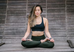 Asian woman practicing yoga and meditation in black sports bra and yoga pants