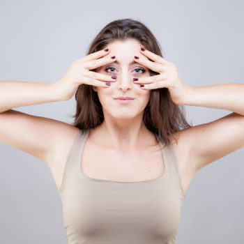 Woman doing face yoga exercises, massaging her face