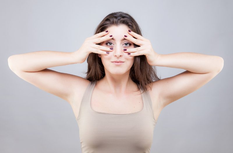 Woman doing face yoga exercises, massaging her face