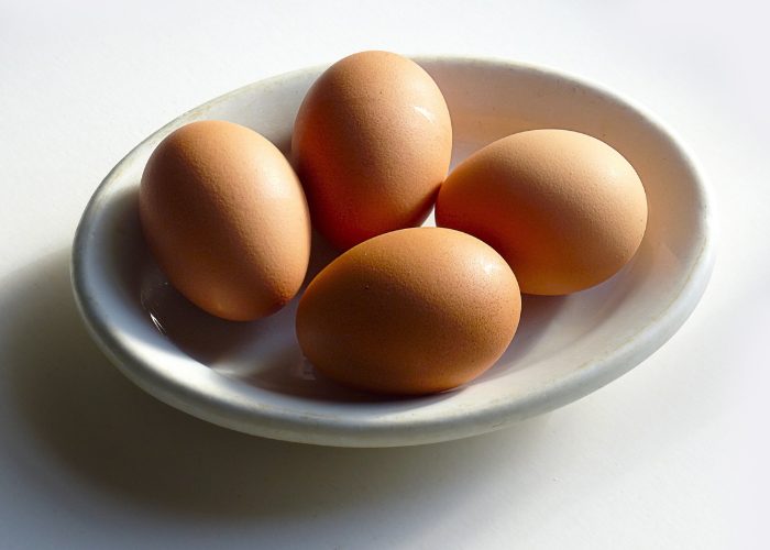 A white bowl with four whole eggs inside
