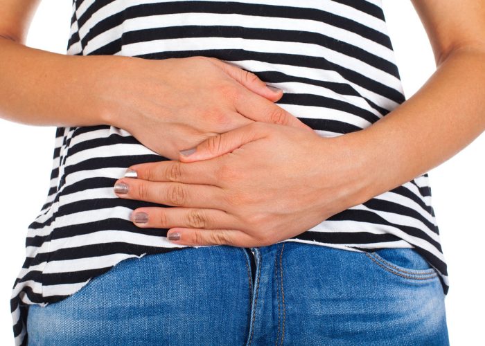 Woman holding onto her bloated belly in discomfort