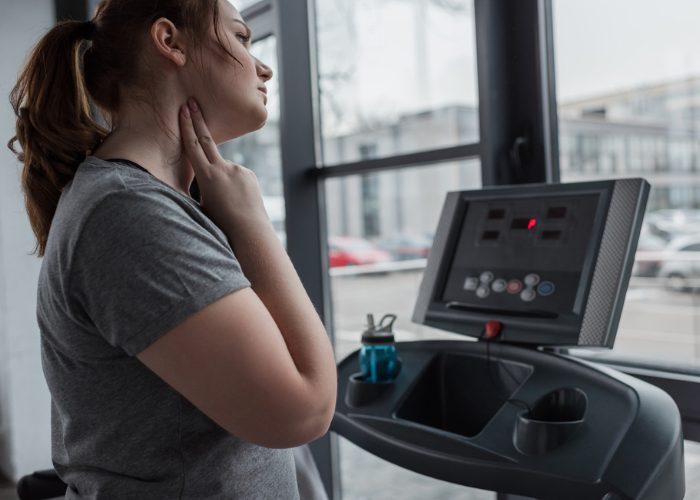 Woman checking her pulse after running on a treadmill