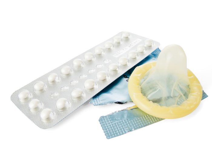 different birth control options like contraceptive pills and a condom on a white table