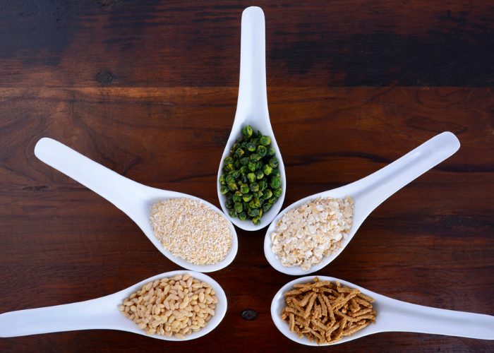 Five white soup spoons filled with different prebiotic foods