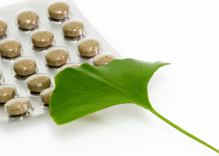 A packet of gingko biloba supplement capsules with a gingko biloba leaf resting on top