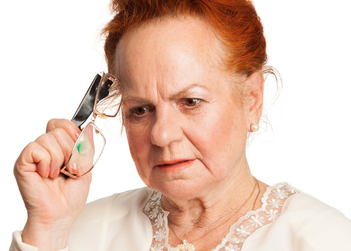 Elderly woman furrowing brow in concentration to recall a distant memory