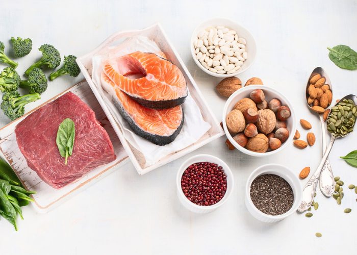 A spread of foods such as meat, fish, nuts, and seeds that are rich in the amino acid isoleucine, laid out on a white table 