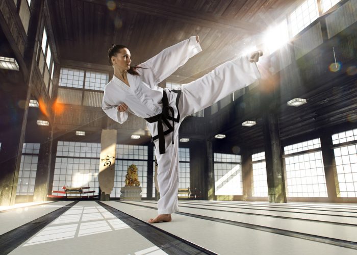 Karate black belt woman in a Japanese dojo practicing a high karate kick