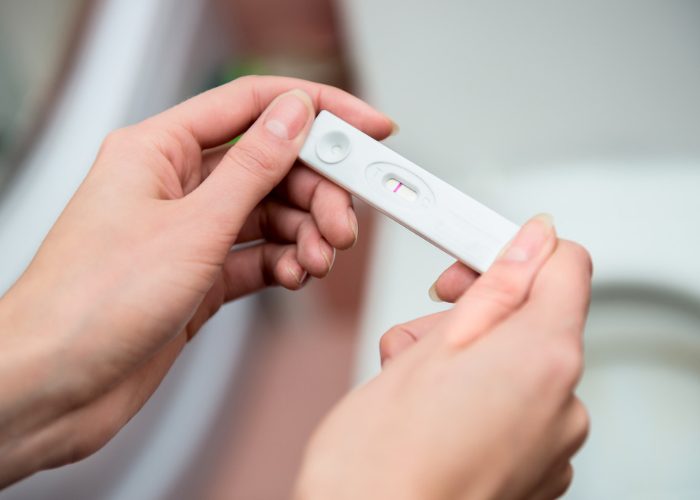 Woman holding a negative pregnancy test she took to see why her period is late