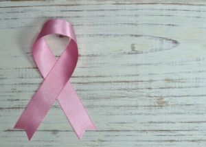Pink breast cancer ribbon on wooden table