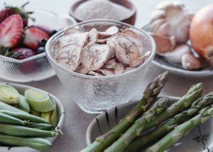 Different prebiotic rich foods like dried banana, asparagus, onions, garlic, berries on a table