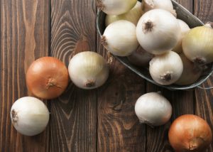 Prebiotic-rich onions in a metal tub on top of a wooden table