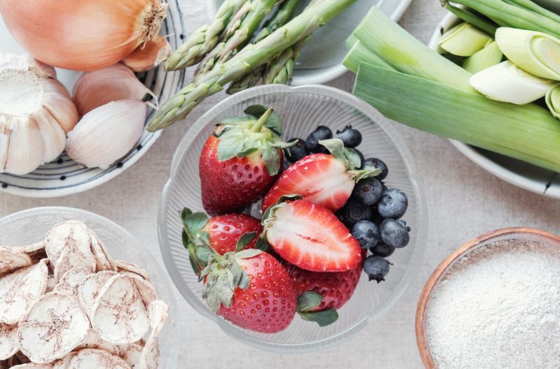 Prebiotic foods such as strawberries, onions, garlic in small dishes on a table